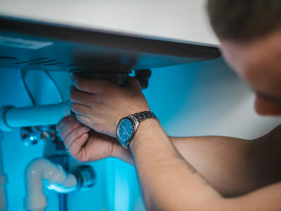 An engineer's hands working on boiler pipework