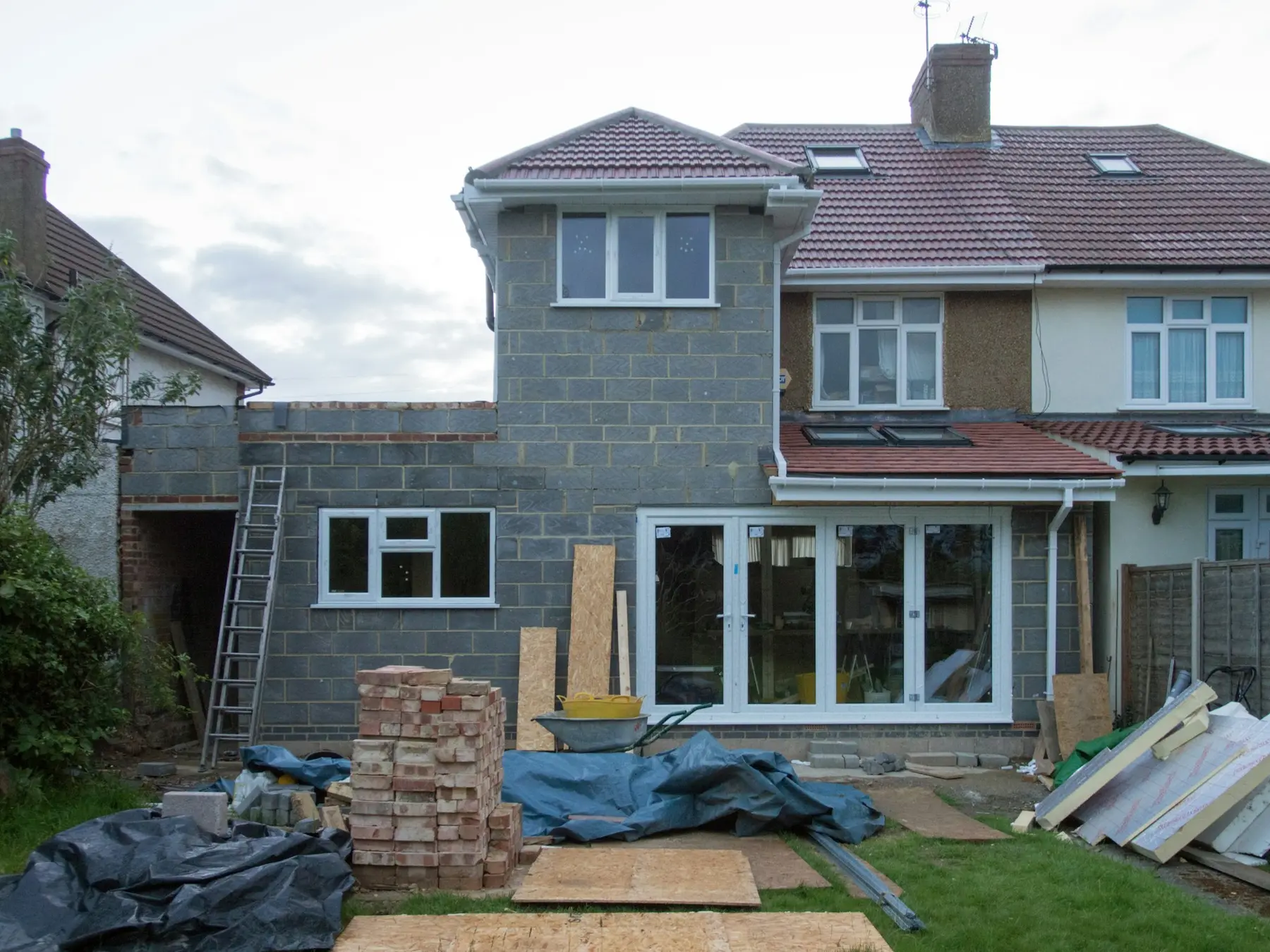 A rear extension in blockwork with new bifold doors, materials stacked on the lawn