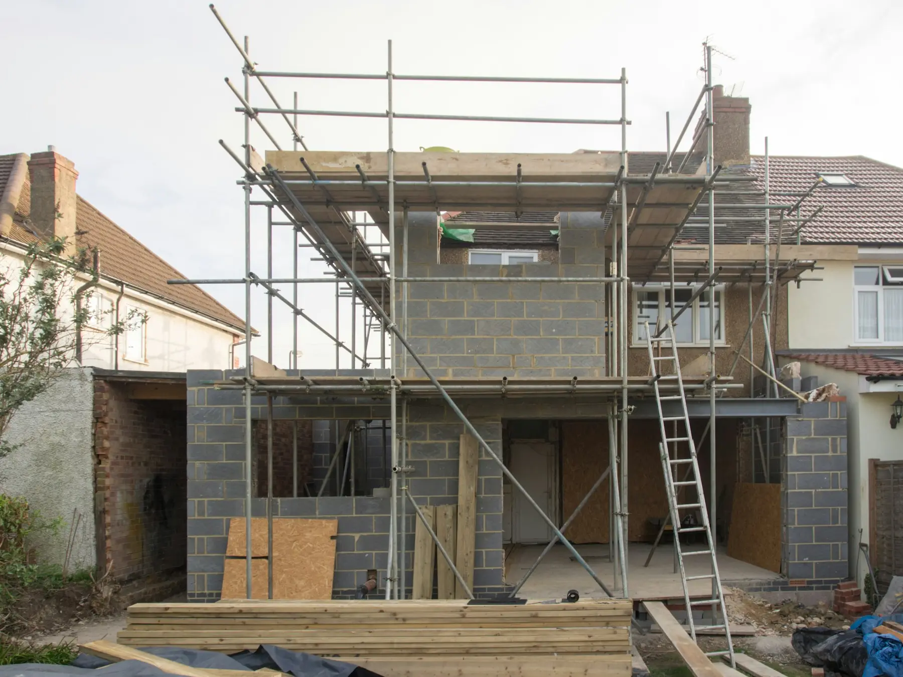 A two-storey house extension in block work, wrapped in scaffolding