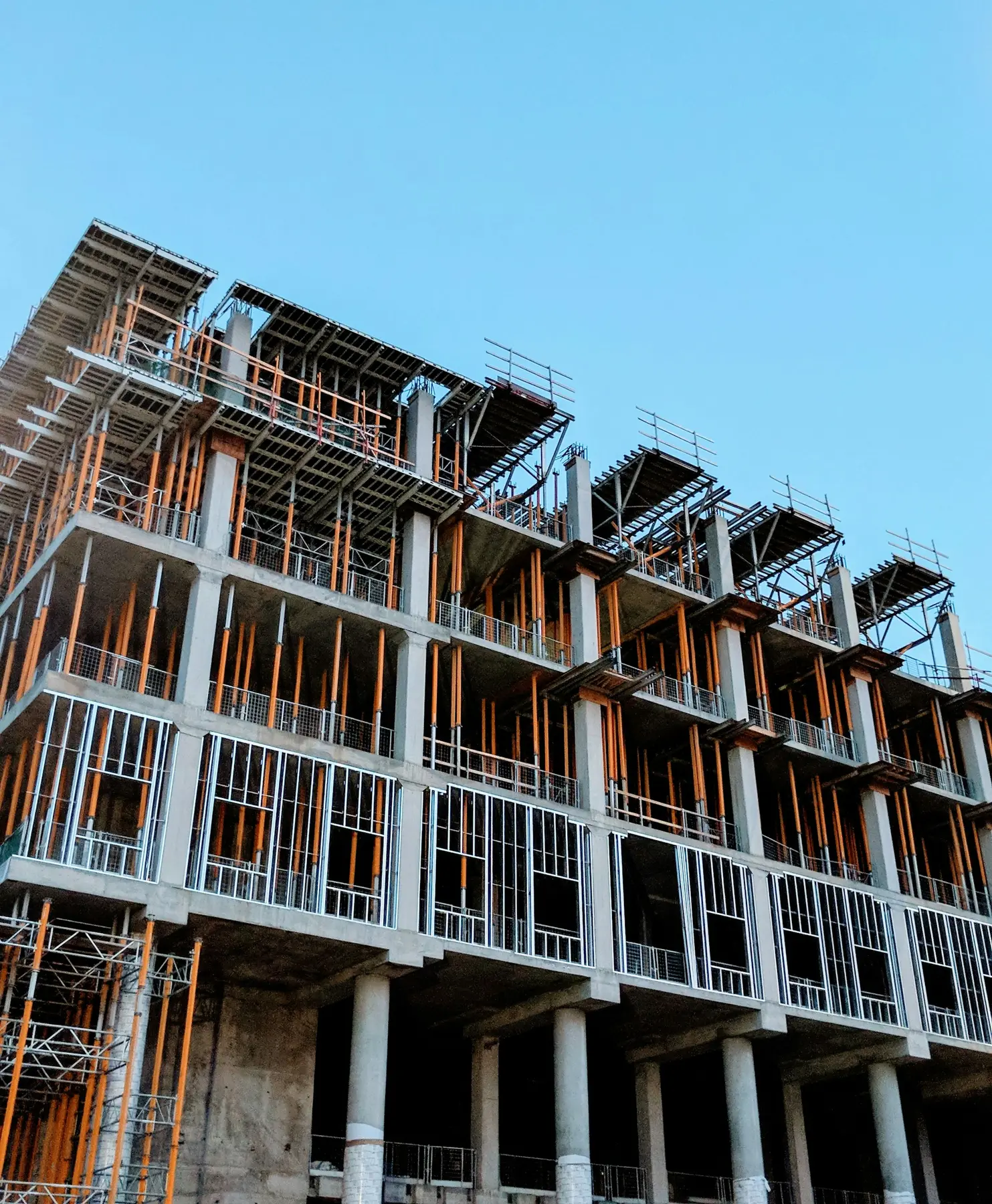 A new steel-framed apartment block with orange frame posts, seen from below