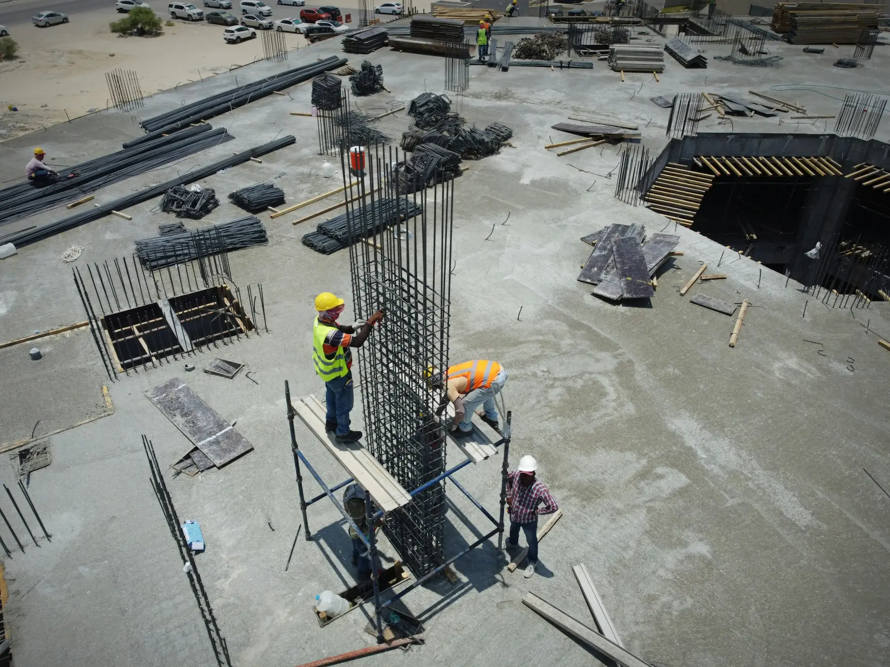 Three builders fixing a rebar column on a concrete slab