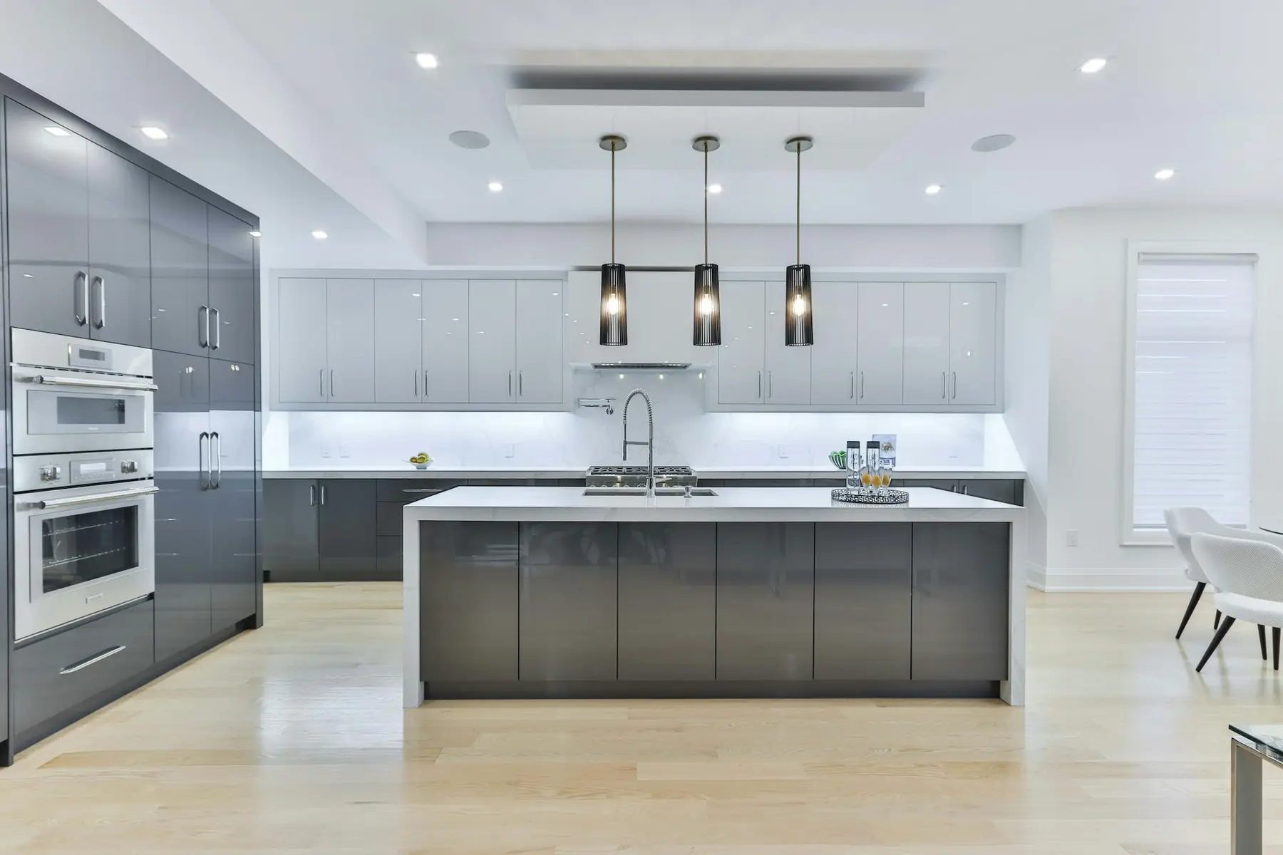 A finished grey handleless kitchen with a long island and three pendant lights
