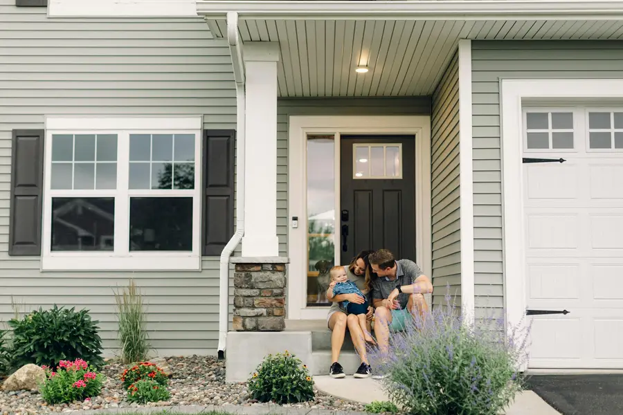 A couple sitting on the front step of their house
