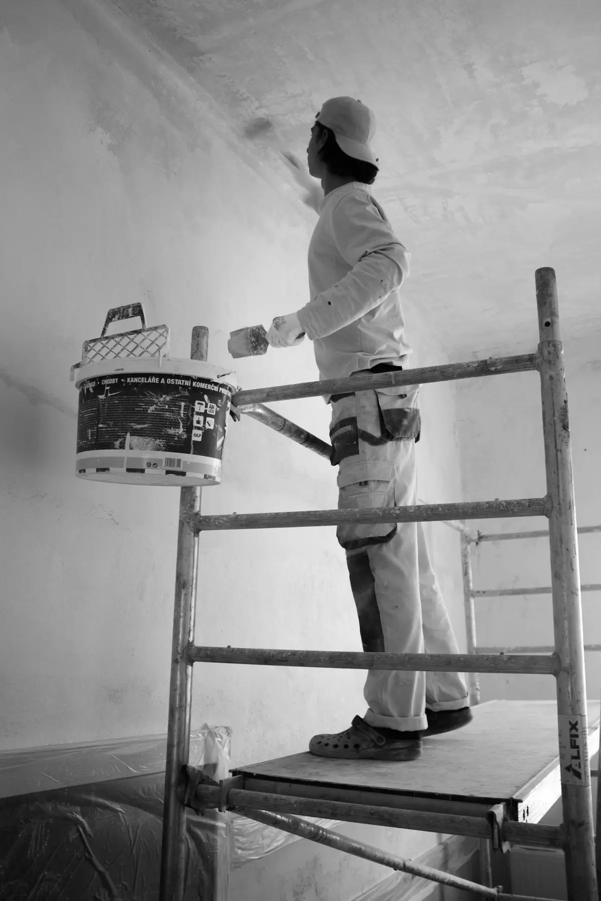 A decorator on a scaffold tower painting a ceiling